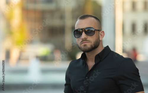 Sexy stylish man in sunglasses. City style. A beautiful and charming man with sunglasses outdoors. © lashkhidzetim
