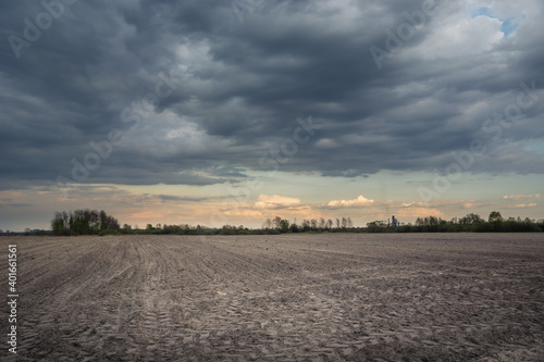 Plowed field, dark rainy clouds on the sky