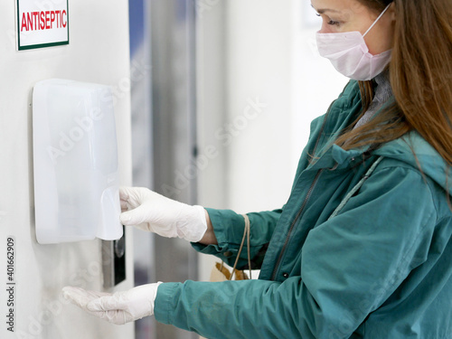 Hands using automatic sanitizer dispenser at supermarket. Disinfectant in a shopping mall during the coronavirus epidemic.