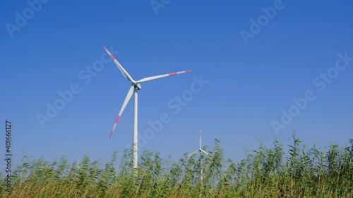 Wind turbine in farm on sunny day. Alternative and sustainable energy.