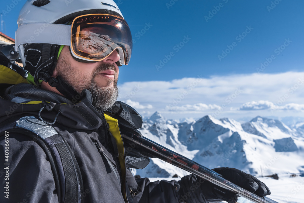 A man with skis stands high in the mountains enjoying the scenery. Go downhill skiing, extreme relaxation A man with skis stands high in the mountains enjoying the scenery. Go downhill skiing, extreme relaxation