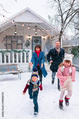 Happy family running out of the porch of the Christmas decorated house outdoor