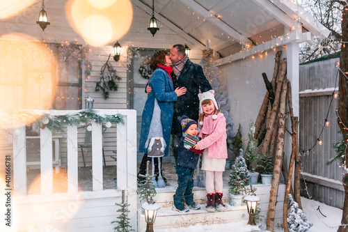 Happy family on the porch of the Christmas decorated house outdoor © len44ik