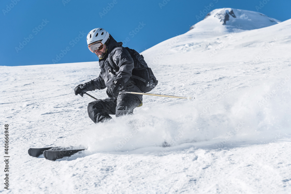 A man with skis stands high in the mountains enjoying the scenery. Go downhill skiing, extreme relaxation A man with skis stands high in the mountains enjoying the scenery. Go downhill skiing, extreme relaxation