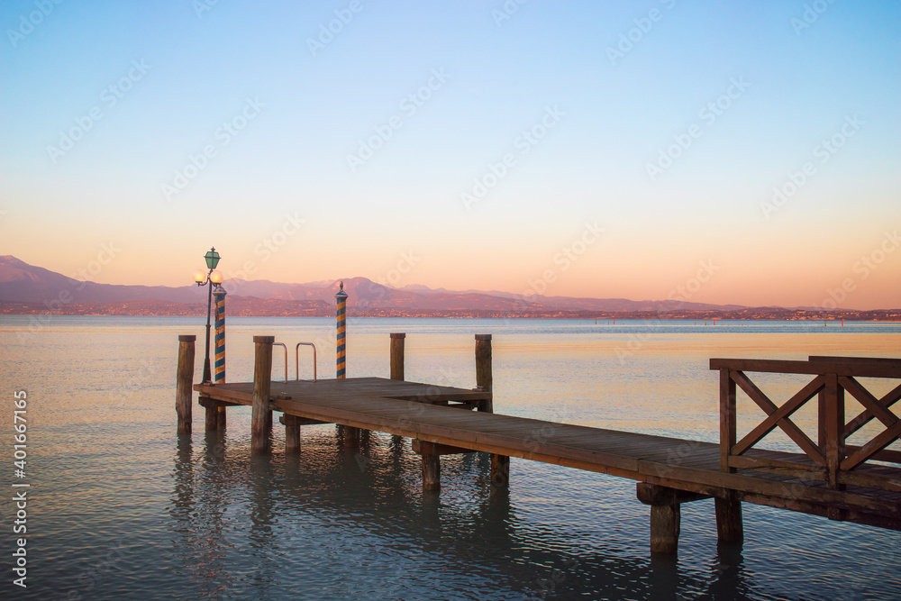 Pier on a garda lake. Sunset over the lake 
