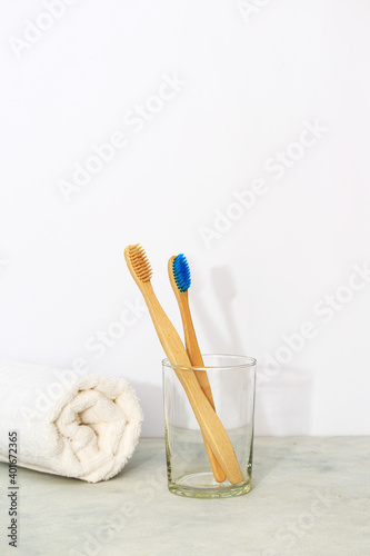 Eco bamboo tooth brushes in a glass and white towel in white background. Concept of zero waste and eco-friendly products