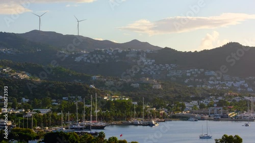 White Aegean houses of Yalikavak next to sea, marina, yachts and windmill background at sunset in Bodrum, Turkey. Bodrum is most popular summer vacation area for tourist in Turkey. 