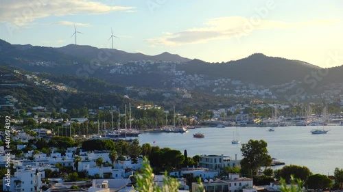 White Aegean houses of Yalikavak next to sea, marina, yachts and windmill background at sunset in Bodrum, Turkey. Bodrum is most popular summer vacation area for tourist in Turkey. 