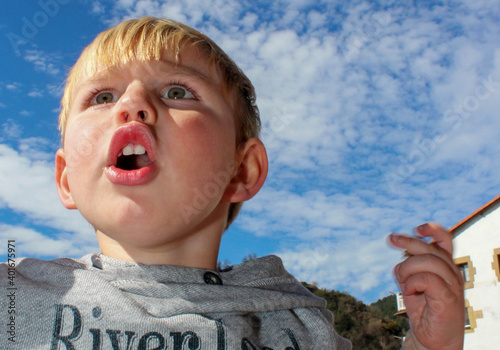 Retrato contrapicado de un niño que grita con el cielo al fondo. Copyspace photo