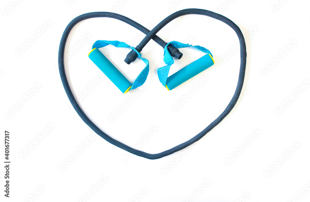 Gym background and fitness equipment and valentine concept. Rubber sports expander in shape of heart on white background Gym background and fitness equipment and valentine concept. Rubber sports expander in shape of heart on white background