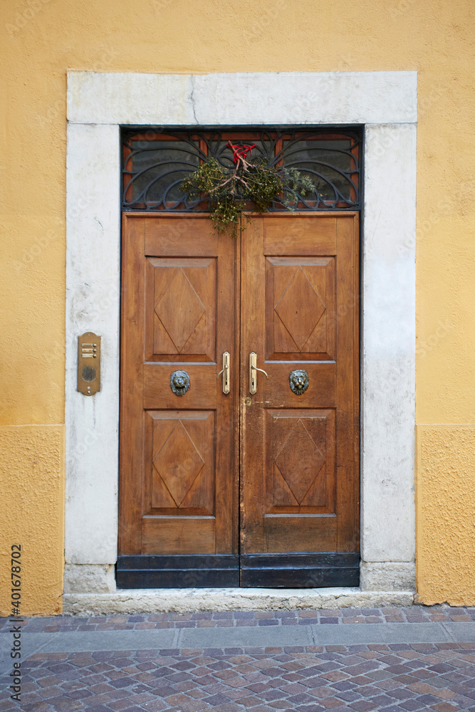 Italian retro wood style front door, the main entrance. Element of the classic Italian facade and architecture Italian retro wood style front door, the main entrance. Element of the classic Italian facade and architecture