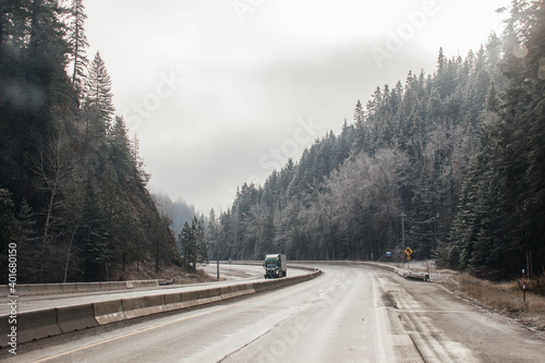 The road in winter, along which cars travel, among snow-covered trees and frost-covered roadsides. Idaho, USA, 11-23-2019 © Liudmila