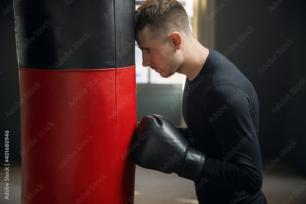 Tired boxer after training. A boxer stands by a punching bag. Workout in the gym. Sweaty athlete in the gym. 4k