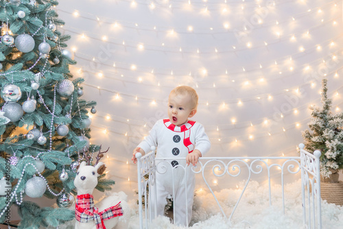 surprised child with open mouth looks at a deer in a christmas snowman costume near the fence