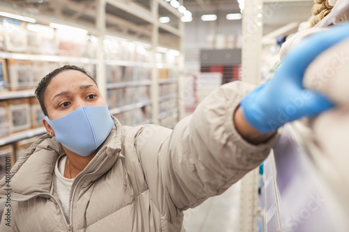 Woman in mask and in protective gloves shopping in supermarket