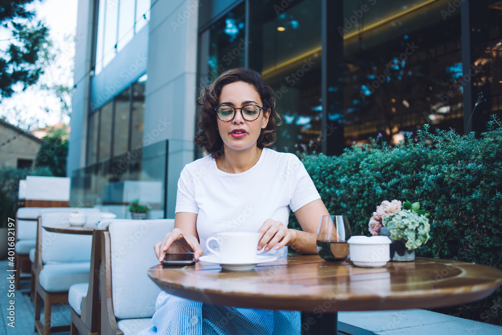 Stylish woman having coffee break in modern outdoor cafe