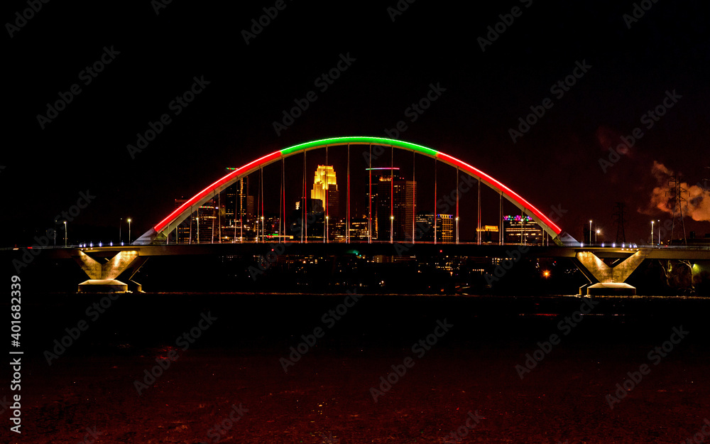Lowry Avenue Bridge colored red and green at dusk on Christmas day with Minneapolis Skyline behind	