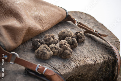 Some black truffles next to a recollection bag and a wooden surface. photo