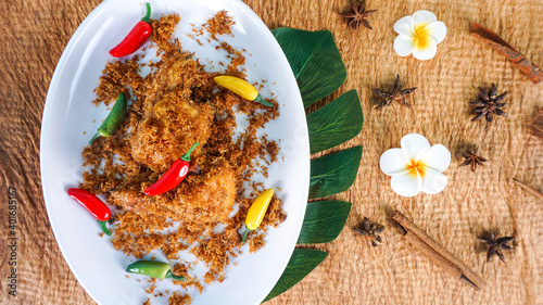 Ayam Serundeng Indonesian Chicken Recipe with Spiced Grated Coconut served on white plate photo