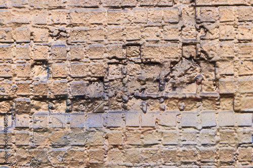 Old brick wall covered with beige and gold paint. Empty background. Close-up.