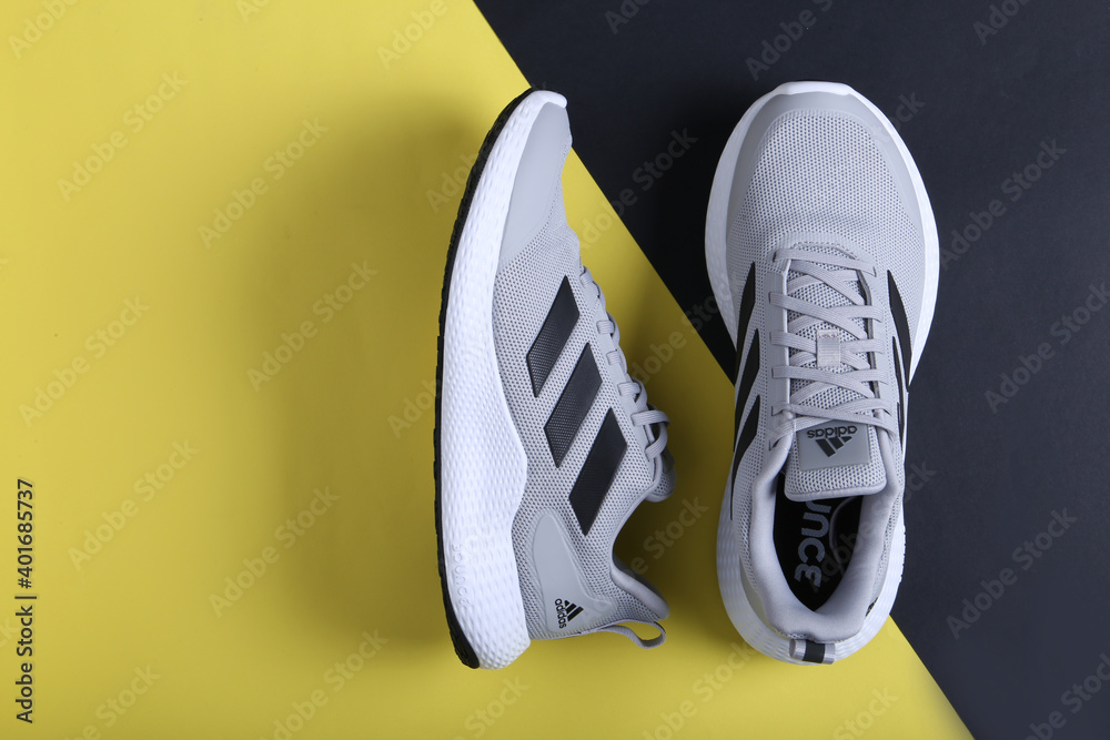 Fotka „Jeddah Saudi Arabia December 26 2020: Grey Adidas Running Shoes.  Adidas, multinational company. Isolated on Black and Yellow background.  Product shots“ ze služby Stock | Adobe Stock