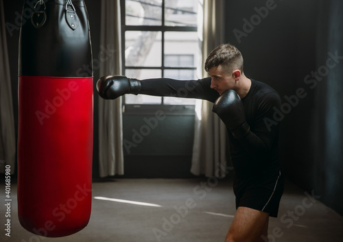 A young athletic man is hitting a boxing bag. Boxer practicing punches in the ring. The athlete strikes with a punching bag. 4k video