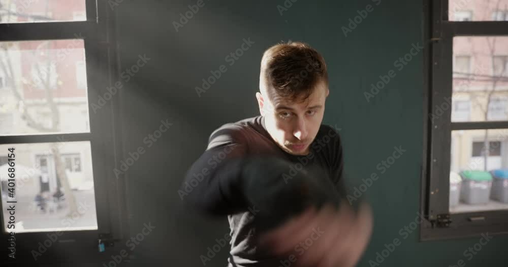 The man is an athlete boxing in the gym. Boxer practicing punches in the ring. Shadow-boxing. The athlete strikes with a punching bag. 4k video The man is an athlete boxing in the gym. Boxer practicing punches in the ring. Shadow-boxing. The athlete strikes with a punching bag. 4k video