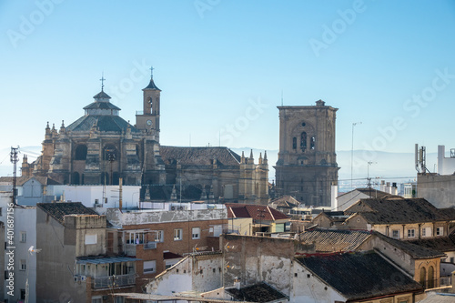 Cathedral and its bell tower behind the roofs of old houses in the city