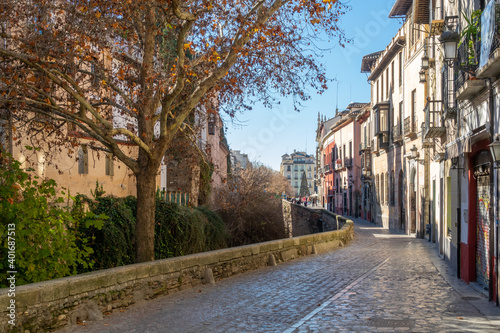 A walk in Granada: View of the Paseo de los Tristes next to the Darro river with Plaza Nueva in the background