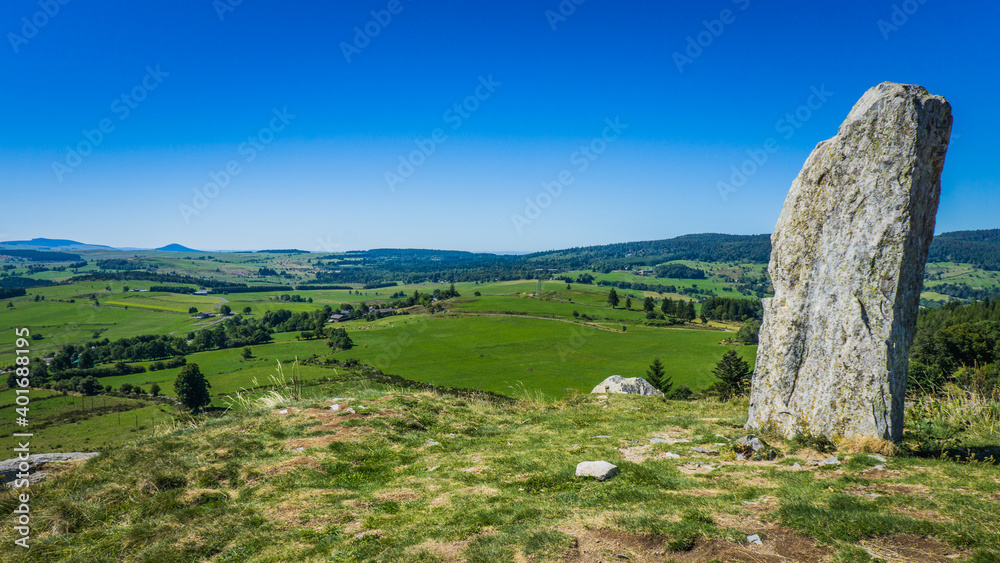 Hiking to the top of the Lizieux Peak (pic du Lizieux) with view of the rural landscape, and in the foreground  a menhir
