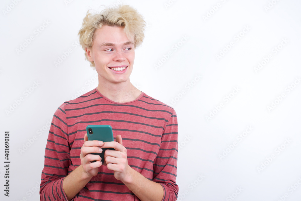 Young handsome Caucasian blond man standing against white background hold telephone hands read good youth news look empty space advert Young handsome Caucasian blond man standing against white background hold telephone hands read good youth news look empty space advert