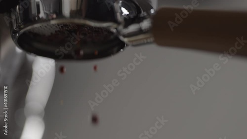 Slow motion low angle bad shot of espresso extraction from naked portafilter into white cup photo