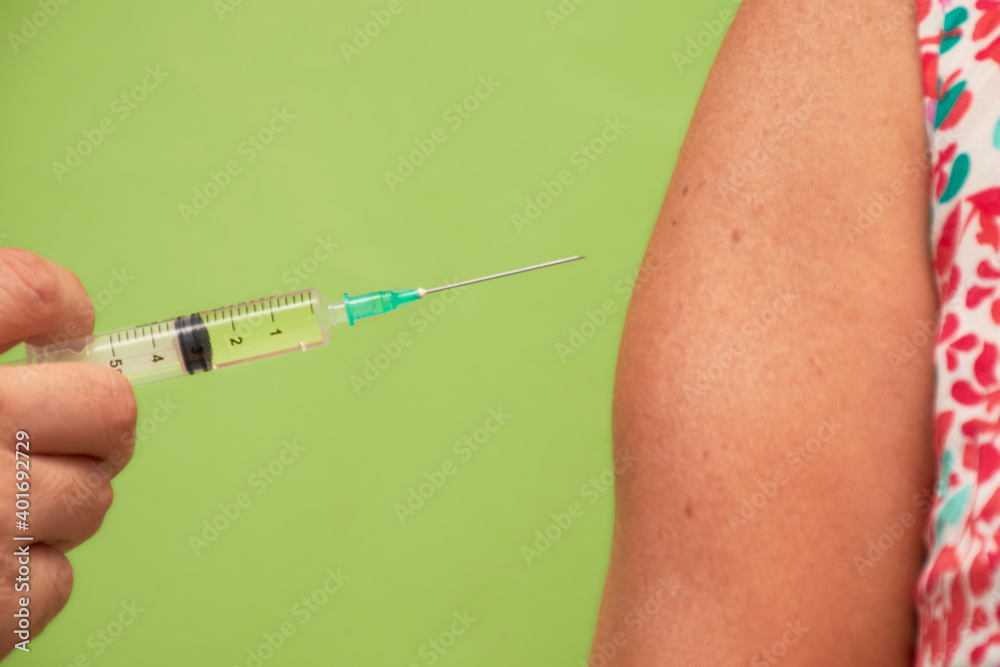 Aplicación de vacuna en brazo sobre fondo verde Aplicación de vacuna en brazo sobre fondo verde