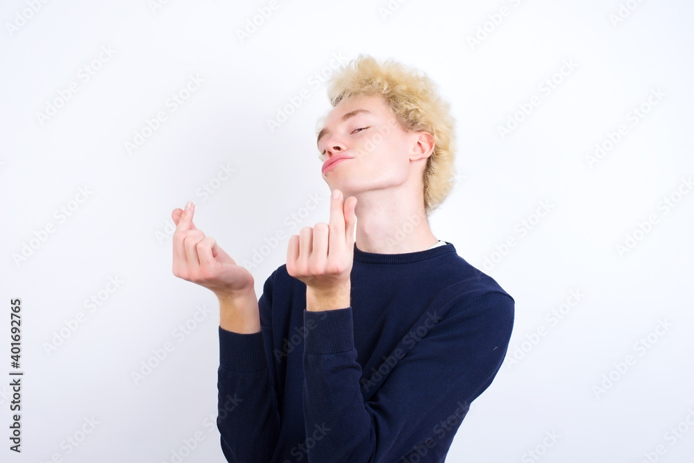Young handsome Caucasian blond man standing against white background doing money gesture with hands, asking for salary payment, millionaire business Young handsome Caucasian blond man standing against white background doing money gesture with hands, asking for salary payment, millionaire business