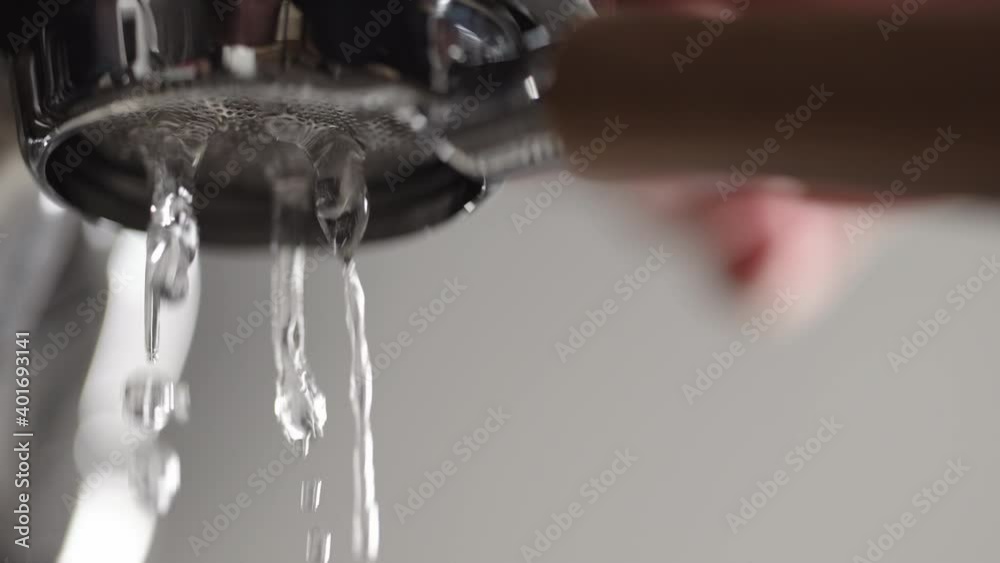 Slow motion low angle shot of rinsing water from naked portafilter Slow motion low angle shot of rinsing water from naked portafilter