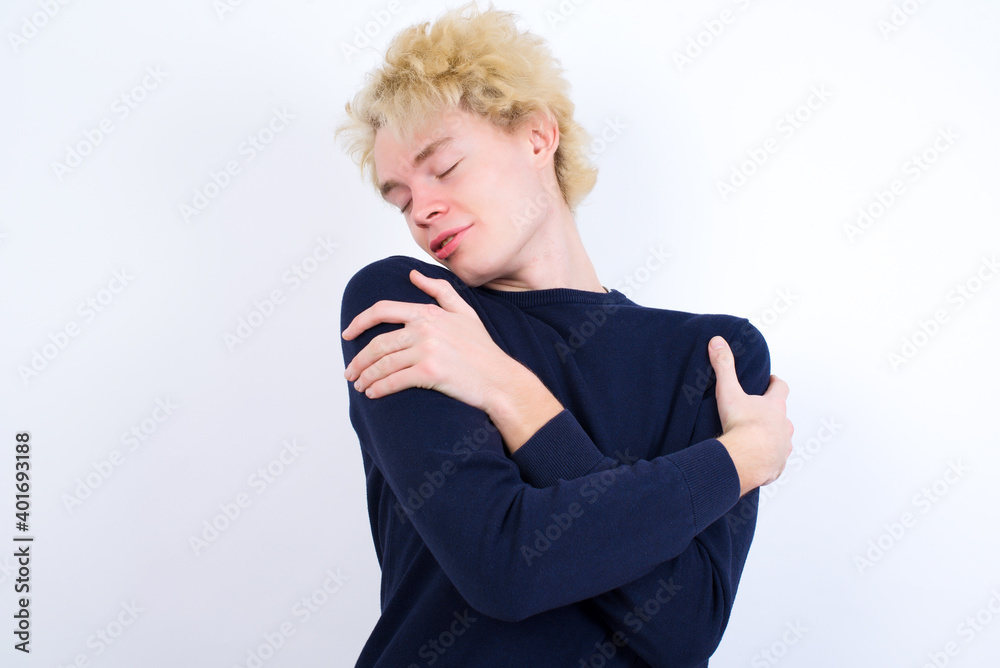 Young handsome Caucasian blond man standing against white background Hugging oneself happy and positive, smiling confident. Self love and self care Young handsome Caucasian blond man standing against white background Hugging oneself happy and positive, smiling confident. Self love and self care