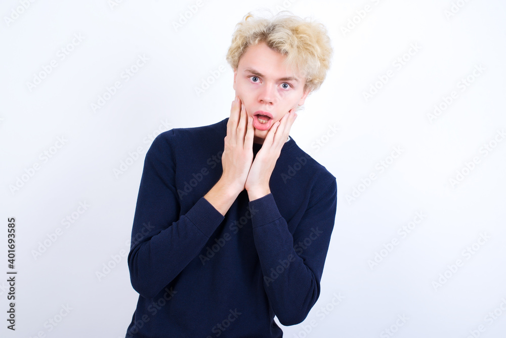 Scared terrified Young handsome Caucasian blond man standing against white background shocked with prices at shop, People and human emotions concept Scared terrified Young handsome Caucasian blond man standing against white background shocked with prices at shop, People and human emotions concept