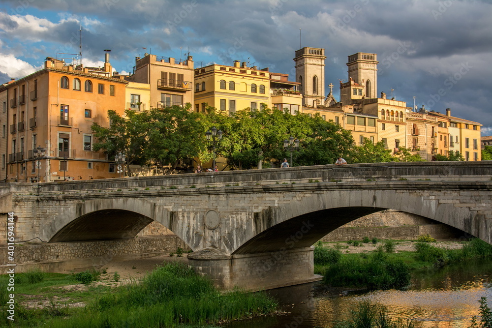 Punte de piedra sobre el rio Onyar, a su paso por la ciudad de Girona, con los edificios de la Plaza de Catalunya de fondo, en el noreste de Catalunya
