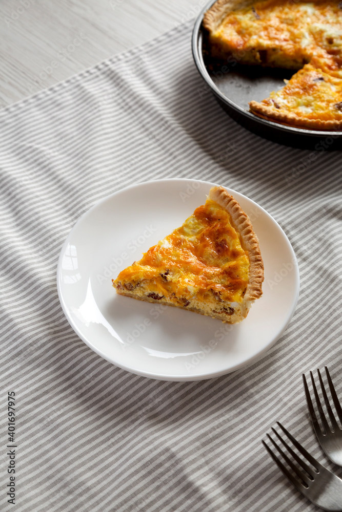 Homemade Bacon Quiche with Eggs and Cheddar Cheese on a white plate, high angle view.