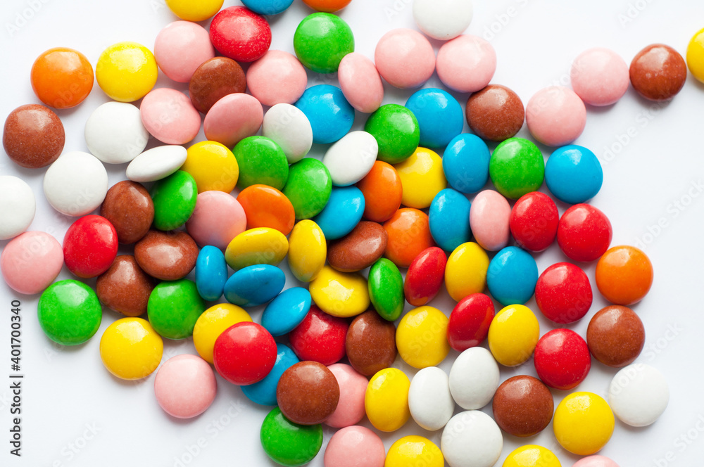 Colored round candies on a white background. Chocolate candies covered with multicolored sugar glaze. Colored round candies on a white background. Chocolate candies covered with multicolored sugar glaze.
