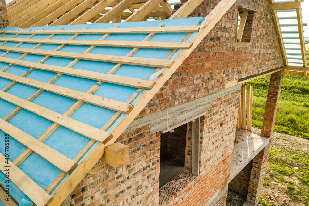 Aerial view of a brick house with wooden roof frame under construction. Aerial view of a brick house with wooden roof frame under construction.