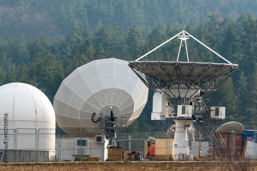 Big satellite dish antennas hidden in green pine tree forest communication center on forest background