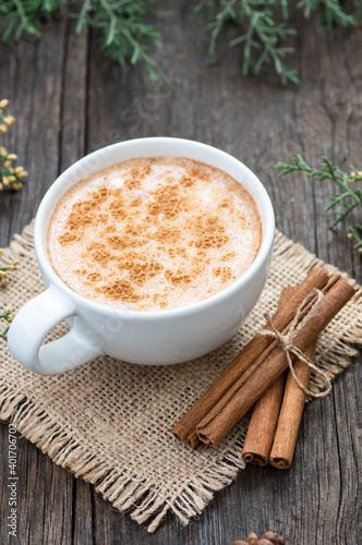 white cup of salep milky traditional hot drink of Turkey with cinnamon powder and sticks on rustic vintage wooden table. Sahlep background photo