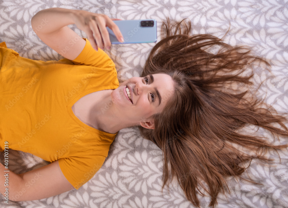 woman lying down smiling watching cell phone woman lying down smiling watching cell phone