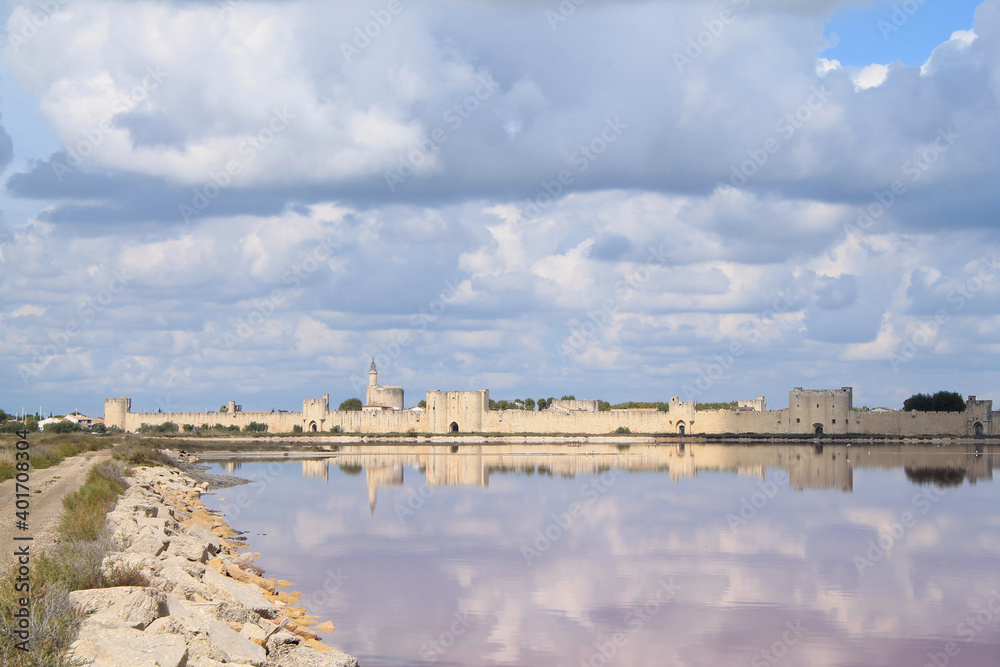 Reflection of the ramparts of the medieval city of Aigues Mortes in the salt marshes, Camargue, France