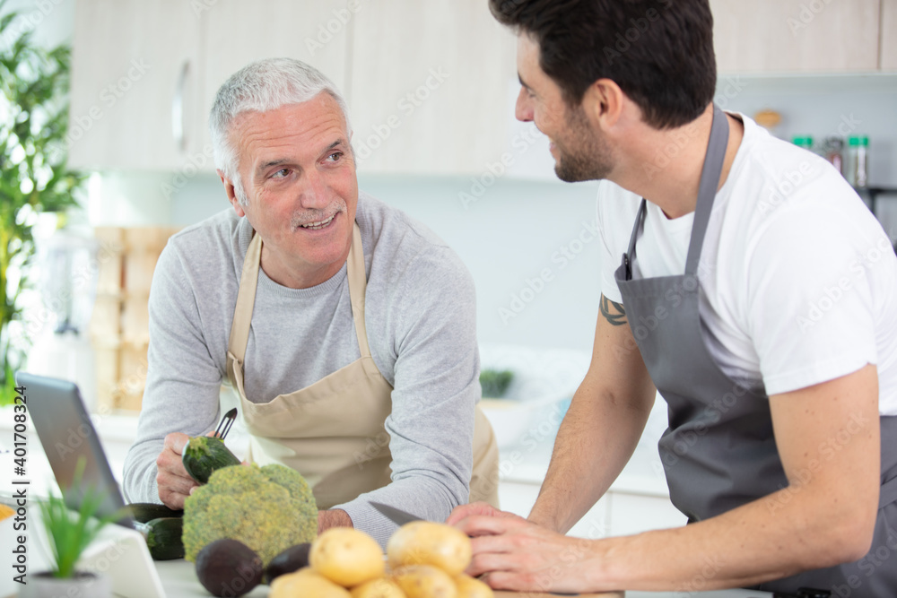 Fototapeta premium adult son with his senior fathercooking in the kitchen