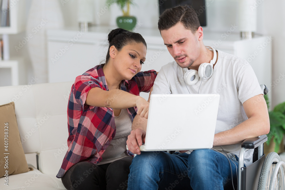 disabled man using laptop sitting next to his girlfriend disabled man using laptop sitting next to his girlfriend