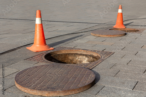 Manhole cover open in street and repair of roads. Accident with sewer hatch in city. Concept of sewage, underground utilities photo