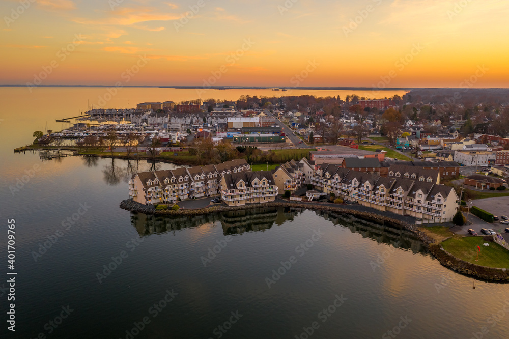 Aerial view of downtown Havre de Grace in Maryland with luxury waterfront apartment complex reflecting in the water as the sun paints the sky orange