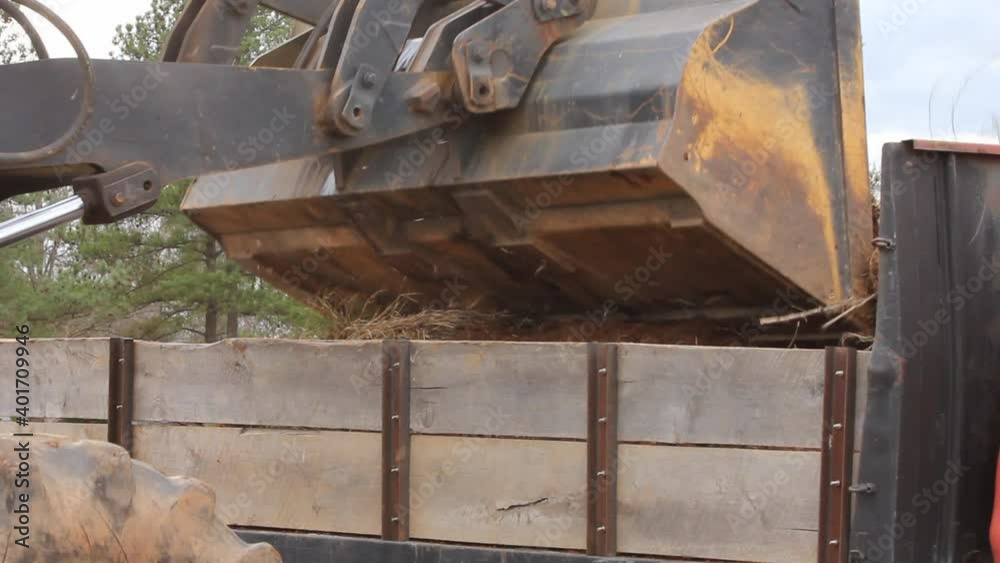 Loader bucket dumps load on to truck with wooden side rails Loader bucket dumps load on to truck with wooden side rails